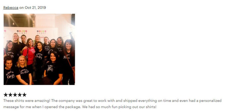 May include: A group of people wearing black t-shirts with white text that says "We're all about the Crazy". The shirts are personalized with different numbers. The group is standing in front of a white wall with colorful balloons.