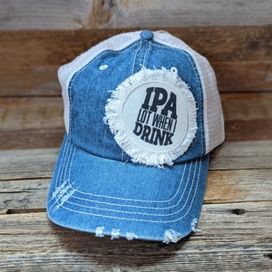 May include: A blue denim trucker hat with a white mesh back. The hat has a white patch with black text that reads "IPA LOT WHEN I DRINK".