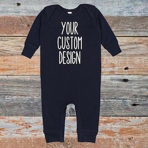 May include: Navy blue baby onesie with long sleeves. The text "YOUR CUSTOM DESIGN" is printed in white on the front. The onesie is made of a soft material and has a round neckline.