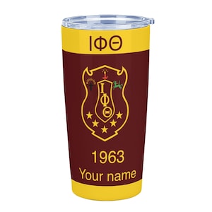 Puede incluir: Un vaso térmico amarillo y granate con tapa transparente. Presenta un escudo dorado con letras griegas y estrellas, el año 1963 y espacio para un nombre. El diseño está impreso en la parte granate del vaso.