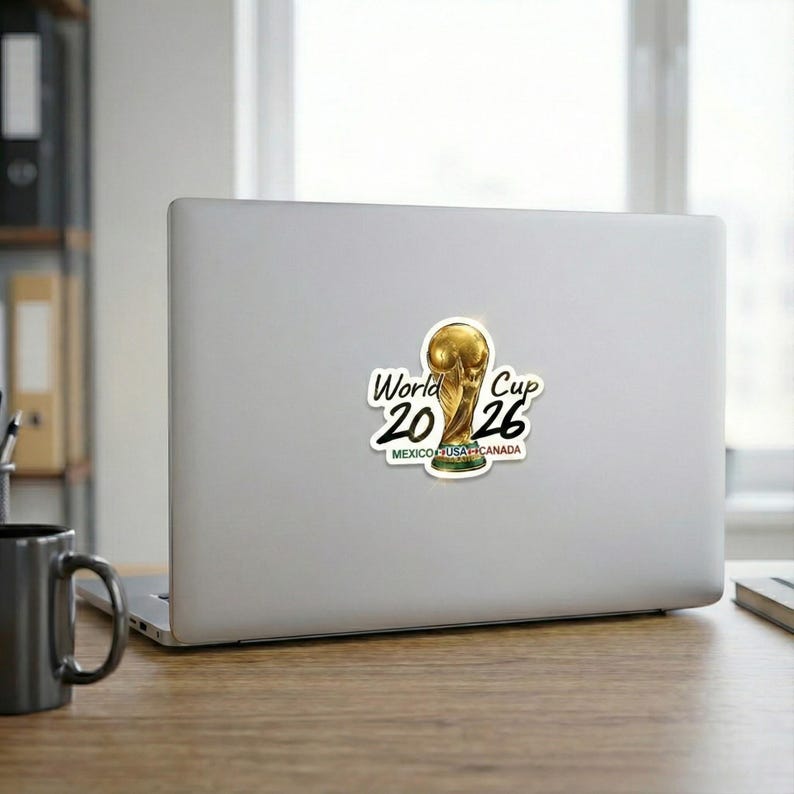 May include: A sticker featuring the FIFA World Cup trophy. The sticker has the text "World Cup 2026" with the trophy in the center. The text "MEXICO USA CANADA" is below the trophy.