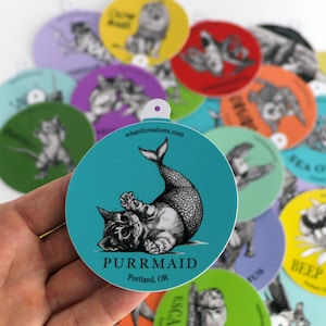 Pode incluir: Um adesivo redondo azul turquesa com uma ilustra&ccedil;&atilde;o em preto e branco de um gato com cauda de sereia. O texto "PURRMAID" &eacute; impresso em preto abaixo do gato. O texto "Portland, OR" &eacute; impresso em preto abaixo do texto "PURRMAID".