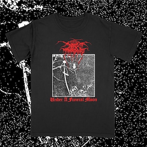 May include: Black t-shirt featuring a red and white graphic. The graphic includes the band name and the text "Under A Funeral Moon". The design is a square image with a figure and a sword. The shirt is a classic crew neck style.