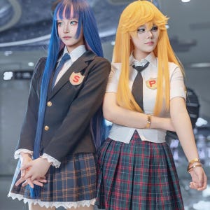 Può includere: Due persone in costumi cosplay ispirati alle uniformi scolastiche. Una indossa un blazer nero, una camicia bianca, una cravatta blu e una gonna a quadri. L'altra indossa una camicia bianca, una cravatta nera e una gonna a quadri.