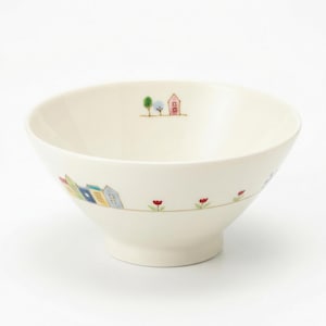 May include: Off-white ceramic bowl with a whimsical village scene. The bowl features a row of colorful houses and red flower accents. The design is repeated around the bowl's exterior, creating a charming, decorative piece.