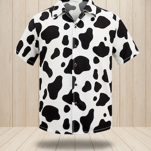 May include: A short-sleeved button-down shirt with a white background and large black cow spots. The shirt has a classic collar and brown buttons. The shirt is made of a lightweight fabric.