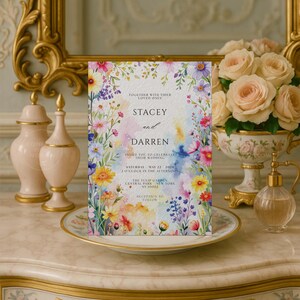 May include: A floral wedding invitation featuring the names "Stacey and Darren" in elegant script. The invitation is surrounded by colorful watercolor flowers and includes event details. The text reads "Invite you to celebrate their wedding."