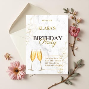 Op de afbeelding: Een verjaardagsuitnodiging met een marmeren achtergrond en gouden accenten. De uitnodiging luidt "Klara's Birthday Party" met datum, tijd en RSVP-informatie. Twee champagneglazen zijn onderaan afgebeeld.
