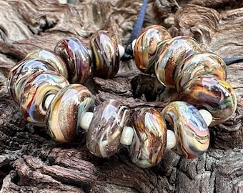 May include: A bracelet featuring a series of colorful, swirled glass beads. The beads are primarily brown, with accents of blue, red, and yellow. Each bead is approximately 0.75 inches in diameter and is strung on a dark cord.