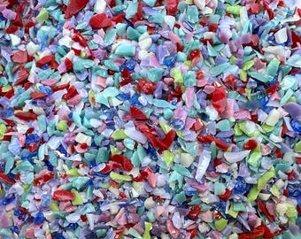 May include: A collection of small, irregular glass shards in a vibrant mix of colors including bright red, light blue, soft lavender, pale pink, lime green, and white. The pieces have a smooth, polished texture and are scattered together.