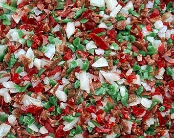 May include: A collection of small, irregular crushed glass fragments in a vibrant mix of translucent red, opaque white, light green, and metallic bronze pieces. The texture is jagged and varied, creating a dense, multi-colored mosaic effect.