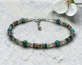 May include: A beaded bracelet featuring round turquoise-colored stones, faceted brown crystal beads, and small silver-toned metal spacers. The bracelet includes a silver-toned metal lobster claw clasp and an adjustable chain extension with a single bead.