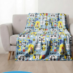 Puede incluir: Una manta azul claro con un patr&oacute;n repetido de Mickey Mouse, estrellas y el nombre "ROBERT". La manta est&aacute; sobre un sof&aacute; gris. Las palabras "CUSTOM NAME" est&aacute;n en la parte inferior.