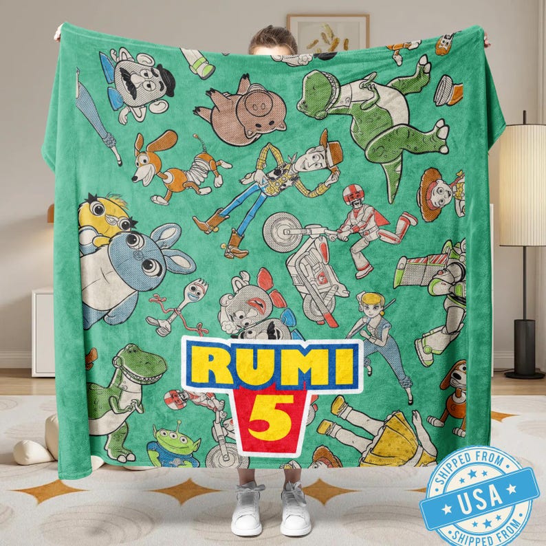 May include: A green blanket featuring cartoon characters from the Toy Story franchise. The blanket has a repeating pattern of characters like Woody, Buzz Lightyear, and Rex. The name "RUMI" and the number "5" are prominently displayed in a logo.