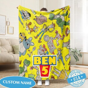 May include: A white ceramic mug with a black handle and the text "But First, Coffee" in a bold, black font. The mug is set against a blurred background, suggesting a cozy setting.