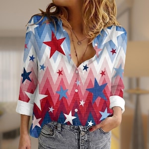 May include: A button-down shirt with a patriotic design featuring red, white, and blue stars and chevron stripes. The long-sleeved shirt has white cuffs and a relaxed fit, suitable for casual wear.