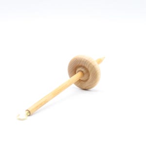 May include: A wooden spinning wheel with a natural finish and a brass hook. The wheel is designed for spinning yarn.