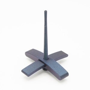 May include: A dark blue, textured drop spindle featuring a cross-shaped base and a long, slender vertical shaft. The object has a matte finish and a uniform, solid color throughout its structure, designed for spinning fibers into yarn.