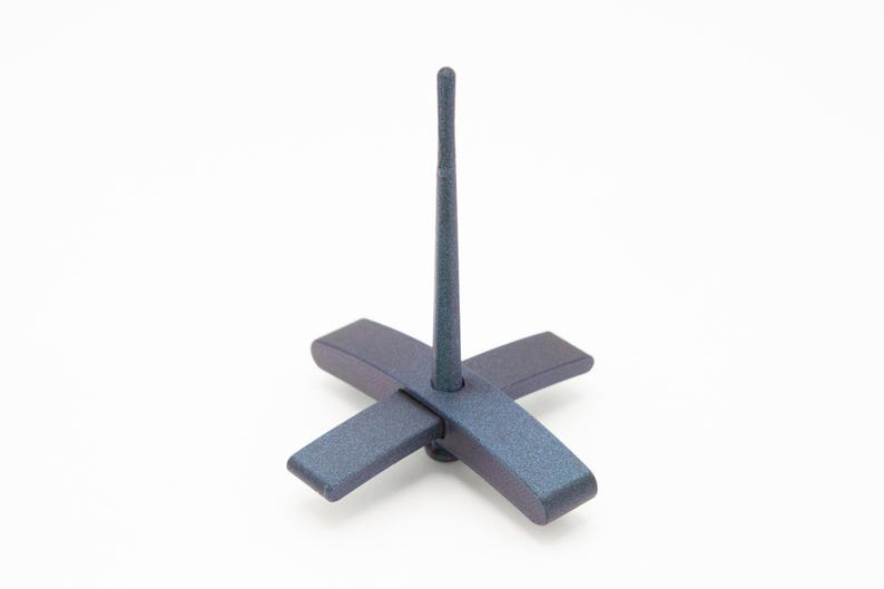 May include: A dark blue, textured drop spindle featuring a cross-shaped base and a long, slender vertical shaft. The object has a matte finish and a uniform, solid color throughout its structure, designed for spinning fibers into yarn.