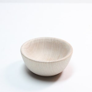 May include: A small, white wooden bowl with a smooth, rounded interior. The bowl is made of light-colored wood and has a natural grain pattern.