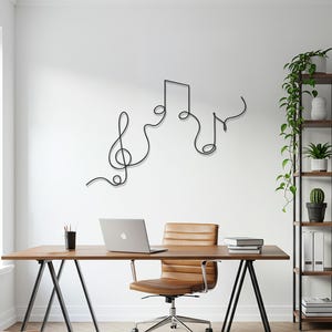 Puede incluir: Decoración de pared de notas musicales de metal negro. La obra de arte presenta una clave de sol y otros símbolos musicales. El arte está montado en una pared blanca sobre un escritorio de madera con un portátil y una silla de oficina.
