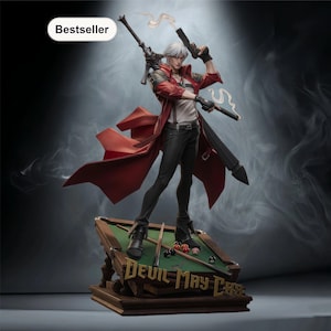 May include: A detailed figurine of a character from "Devil May Cry" stands on a miniature pool table. The figure wears a red coat, black trousers, and holds two pistols. A rifle is slung over the shoulder. The base reads "Devil May Cry".