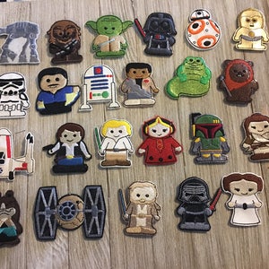 May include: A collection of embroidered Star Wars character patches, including Yoda, Darth Vader, and R2-D2. The patches feature various characters and vehicles from the Star Wars franchise, with detailed stitching and vibrant colors. These patches are ideal for decorating clothing or accessories.