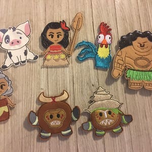 May include: A collection of colorful fabric appliques featuring characters from a popular animated movie. The appliques include a pig, a girl, a rooster, a man, a woman, a bull, and a coconut-like creature. These are likely for crafting or decorating.