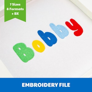 Puede incluir: Un archivo de bordado con el nombre Bobby cosido en letras de colores sobre un fondo de tela blanca. Las letras son verdes, amarillas, azul oscuro, azul claro y rojas. Una pancarta verde en la esquina muestra 7 Sizes, 8 Formats + BX.