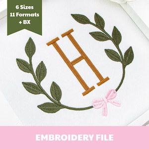 May include: An embroidery design featuring a large brown letter H centered within a wreath of dark green leaves. A small light pink bow is stitched at the bottom of the wreath. The text 6 Sizes 11 Formats + BX appears in a green banner, and EMBROIDERY FILE is at the bottom.
