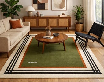 May include: A rectangular area rug featuring a large olive green center panel, a burnt orange border, and a wide cream-colored outer frame with black geometric line patterns. The text DecorArtLoom is printed in white on the green section.