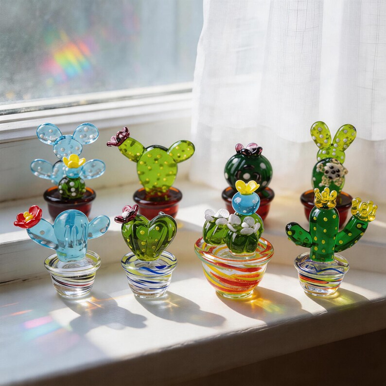 Puede incluir: Colecci&oacute;n de esculturas de cactus de vidrio de colores en varias formas y tama&ntilde;os. Los cactus est&aacute;n en macetas peque&ntilde;as, algunas con dise&ntilde;os a rayas. El vidrio es transparente, con detalles como flores y espinas.