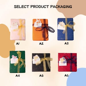 May include: Six rectangular gift packages labelled A1 through A6, each wrapped in solid-coloured paper with gold speckles, tied with sheer ribbons, and adorned with a floral gift tag. The text SELECT PRODUCT PACKAGING appears at the top.