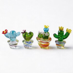 Puede incluir: Cuatro figuras de cactus de cristal de colores en macetas peque&ntilde;as. Los cactus son de varios tonos de verde y azul, con detalles de flores rojas, amarillas y blancas. Las macetas tienen dise&ntilde;os a rayas multicolores.