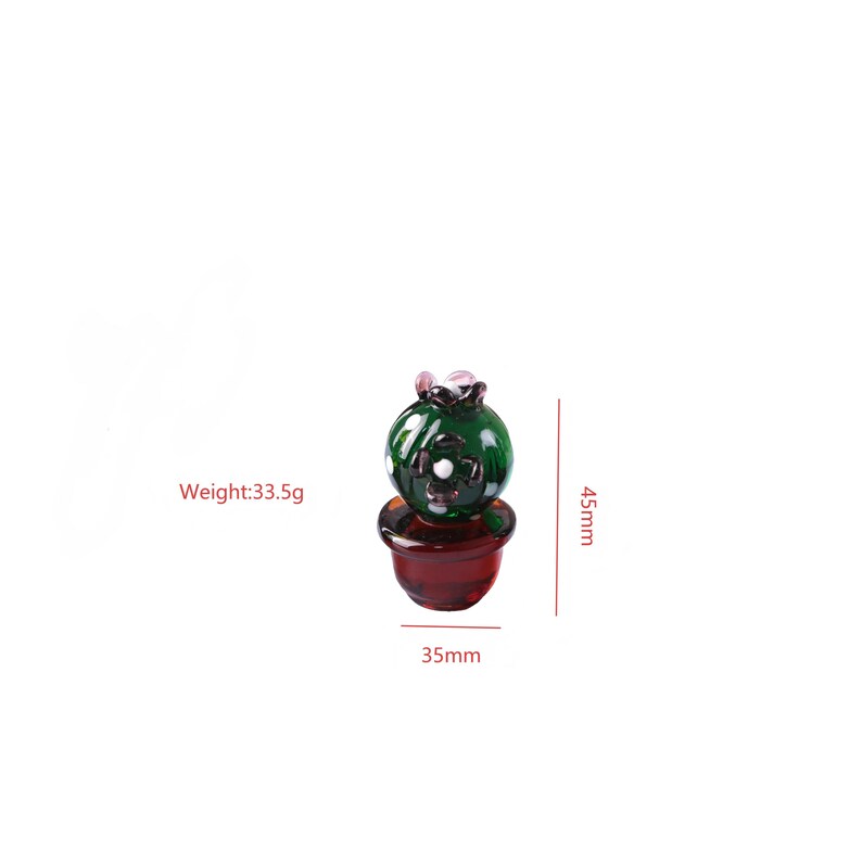 Puede incluir: Una figura de cactus de cristal en miniatura. El cactus verde tiene detalles blancos y est&aacute; colocado en una maceta de color rojo oscuro. La figura mide 4,5 cm de alto y 3,5 cm de ancho, con un peso de 33,5 g.