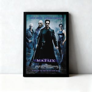 May include: Framed movie poster for the film "The Matrix" featuring Keanu Reeves, Laurence Fishburne, and others. The poster has a black frame and a dark color scheme with the word "MATRIX" prominently displayed.