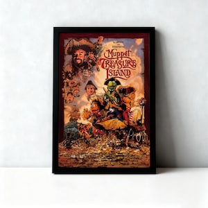 Op de afbeelding: Een ingelijste filmposter voor "Muppet Treasure Island" met een collage van Muppet-personages in piratenkleding. De poster heeft een zwarte lijst en een kleurrijk ontwerp met de filmtitel prominent weergegeven.