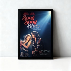 May include: A framed movie poster for "Song Sung Blue" featuring Hugh Jackman and Kate Hudson. The title is in a glittery red font, with the actors' names at the top. The image shows the actors singing on stage, with a blue spotlight.