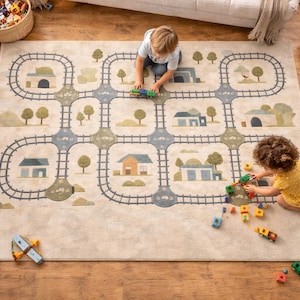 Könnte beinhalten: Ein rechteckiger beiger Teppich mit einem Eisenbahnstrecken-Design, das Häuser, Bäume und eine Eisenbahn zeigt. Zwei Kinder spielen mit Spielzeugzügen und -blöcken auf dem Teppich. Der Teppich liegt auf einem Holzboden.