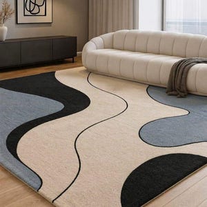 Elegant Minimalist Living Room with Abstract Art Rug, Curved Cream Sofa, and Warm Neutral