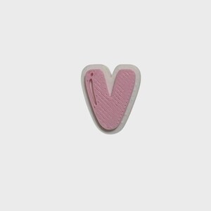 May include: A letter V shaped patch featuring a textured light pink surface layered over a slightly larger, smooth, translucent white base. The pink section displays a subtle, linear, wood-grain-like pattern across its entire surface.