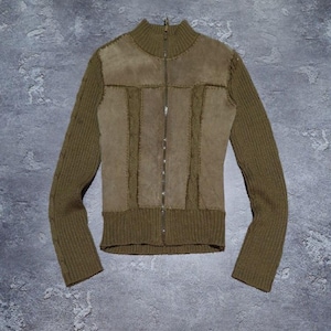 May include: Olive green zip-up jacket with a high collar. The jacket features a suede-like panel across the chest and upper back, with knitted sleeves and lower hem. The zipper runs down the center of the jacket.