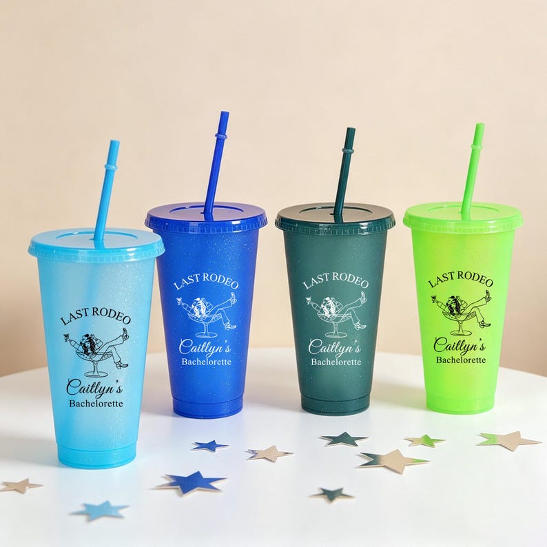 K&ouml;nnte beinhalten: Vier bunte Plastikbecher mit Deckeln und Strohhalmen. Jeder Becher hat eine andere Farbe: hellblau, blau, gr&uuml;n und limettengr&uuml;n. Der Text "LAST RODEO" und "Caitlyn's Bachelorette" ist auf jedem Becher aufgedruckt.