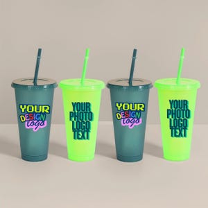 Puede incluir: Cuatro vasos de plástico reutilizables con tapas y pajitas. Dos son verde azulado, dos son verde neón. Cada vaso tiene el texto "YOUR DESIGN logo" o "YOUR PHOTO LOGO TEXT" en un diseño colorido. Las pajitas y las tapas están coordinadas.