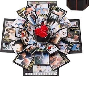 May include: A black explosion box filled with photos, red roses, and decorative details. The box is open, displaying multiple layers of photos and embellishments. A separate black gift box with a red ribbon is also visible.