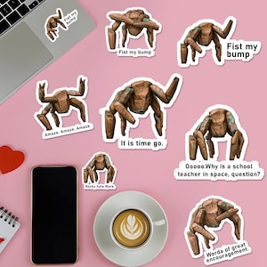 May include: A collection of brown and teal stickers featuring a stylized robotic creature in various poses. Some stickers have text: "Fist my bump", "Amaze. Amaze. Amaze.", "It is time go.", "Rocky hate Mark.", "Ooooo.Why is a school teacher in space, question?", and "Worda of great encouragement."