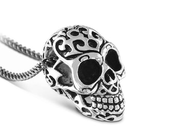 May include: Silver skull pendant necklace with intricate floral designs and black eye details. The pendant is attached to a silver chain.