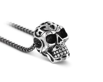 May include: A silver skull pendant necklace with intricate details and a black chain.