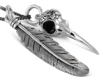 May include: A silver necklace with two pendants: a detailed feather and a bird skull with a floral design.
