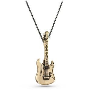May include: A gold-colored electric guitar pendant necklace with a black chain. The guitar pendant has a detailed design with a pickguard and knobs.